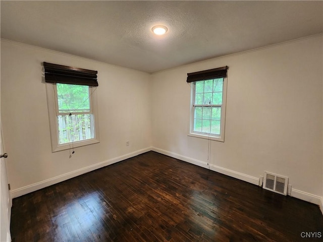empty room with ornamental molding, dark wood-style flooring, baseboards, and a textured ceiling