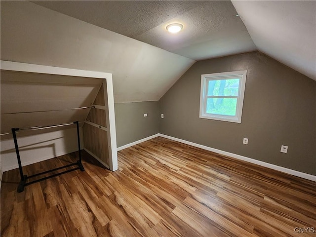 bonus room with wood finished floors, baseboards, and vaulted ceiling