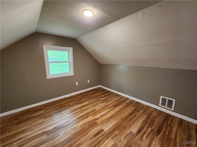 additional living space featuring wood finished floors, baseboards, and vaulted ceiling