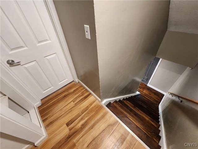 stairway with wood finished floors and baseboards