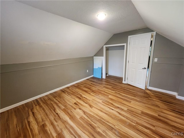 bonus room with light wood finished floors, baseboards, and lofted ceiling