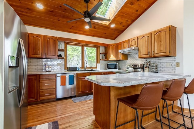 kitchen featuring appliances with stainless steel finishes, open shelves, a peninsula, a sink, and under cabinet range hood