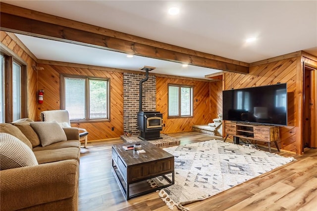 living area featuring wooden walls, beamed ceiling, a wood stove, wood finished floors, and recessed lighting