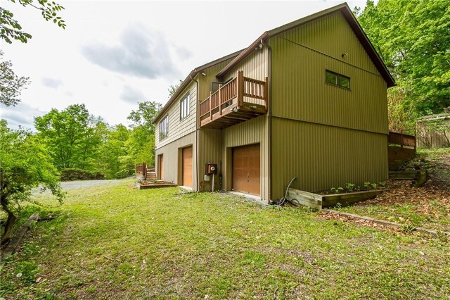 back of property featuring a lawn, an attached garage, and a balcony