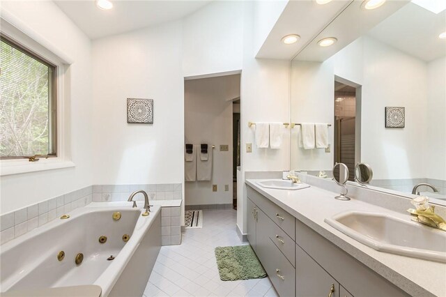 bathroom with tile patterned floors, a tub with jets, double vanity, and recessed lighting