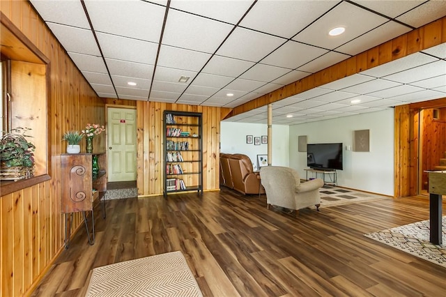 living room with wooden walls, wood finished floors, recessed lighting, and baseboards