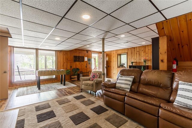 living room featuring healthy amount of natural light, wood walls, wood finished floors, and recessed lighting