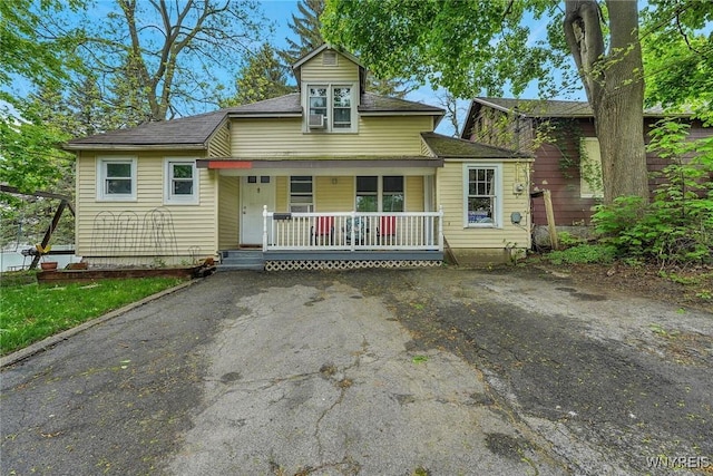 bungalow with a porch and asphalt driveway
