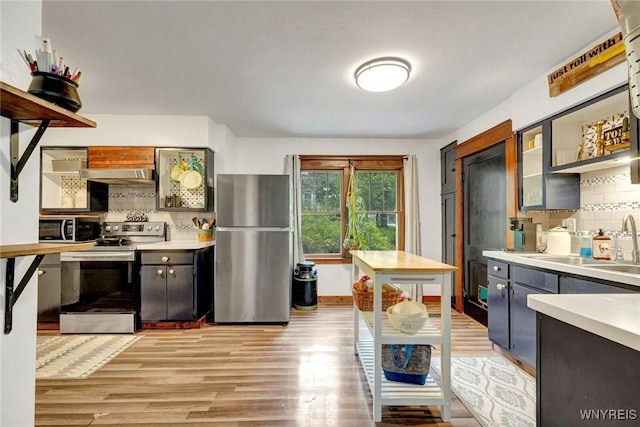 kitchen with appliances with stainless steel finishes, a sink, under cabinet range hood, and backsplash