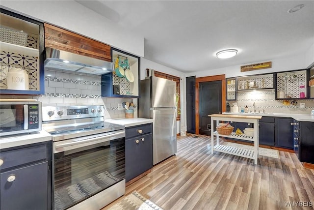 kitchen with stainless steel appliances, open shelves, tasteful backsplash, and light wood-style floors