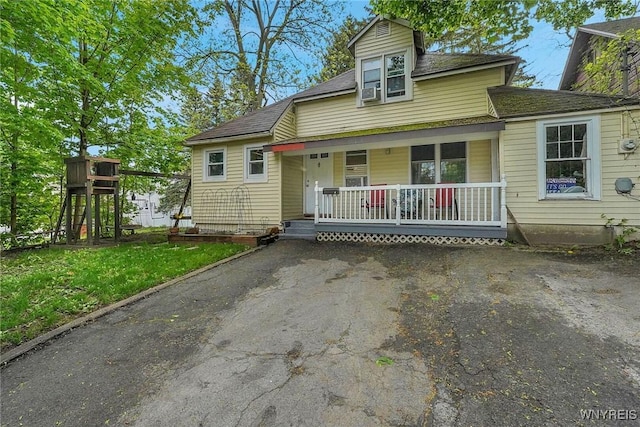 bungalow-style home with a porch, driveway, and a shingled roof