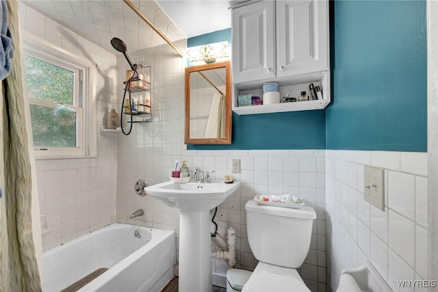 bathroom featuring toilet, shower / bath combination with curtain, a sink, and tile walls