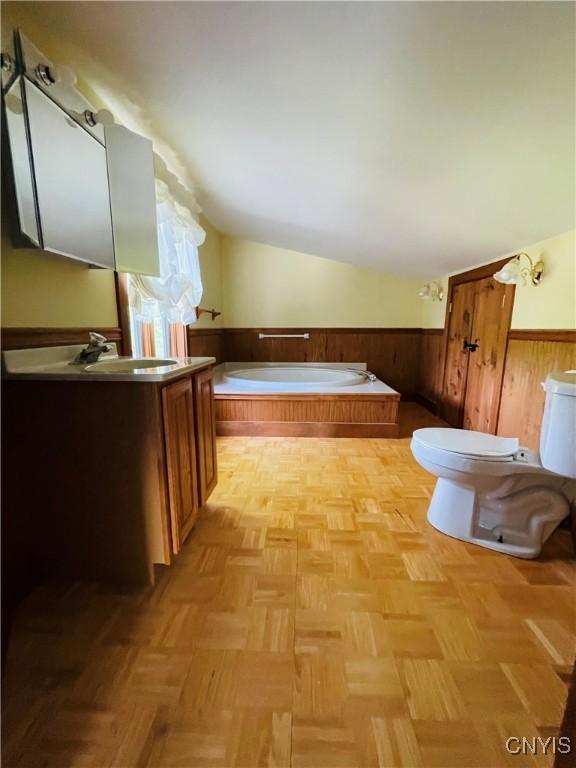 62 Pleasant Valley Rd, Groton, NY 13073 - full bath with lofted ceiling, wainscoting, toilet, vanity, and a garden tub