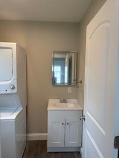 34 Sunnyside Dr, Elmira, NY 14905 - laundry room featuring a sink, stacked washing machine and dryer, baseboards, and dark wood-style flooring