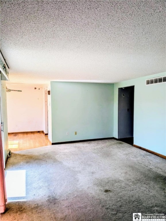 spare room featuring carpet floors, a textured ceiling, and baseboards