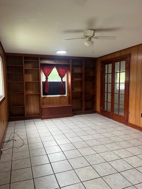 203 Church St, Catharine, NY 14869 - unfurnished living room with wood walls, built in features, a ceiling fan, and light tile patterned flooring