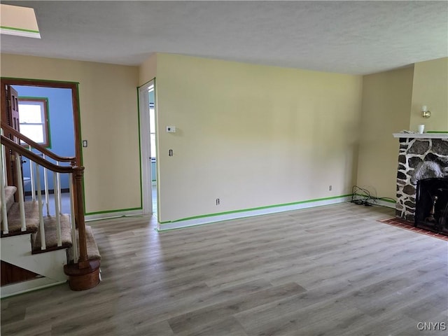 343 N Peterboro St, Lenox, NY 13032 - unfurnished living room with wood finished floors, baseboards, stairway, and a stone fireplace