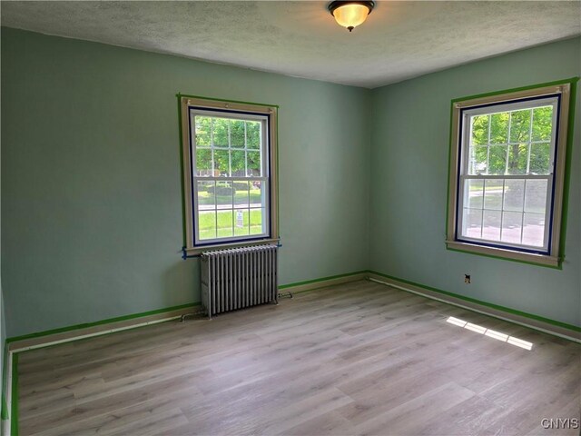 343 N Peterboro St, Lenox, NY 13032 - unfurnished room with radiator heating unit, wood finished floors, healthy amount of natural light, baseboards, and a textured ceiling