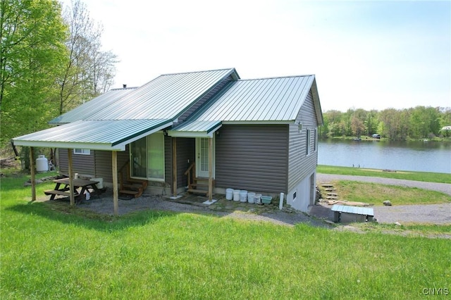 view of front of home with entry steps, a water view, a front lawn, and metal roof