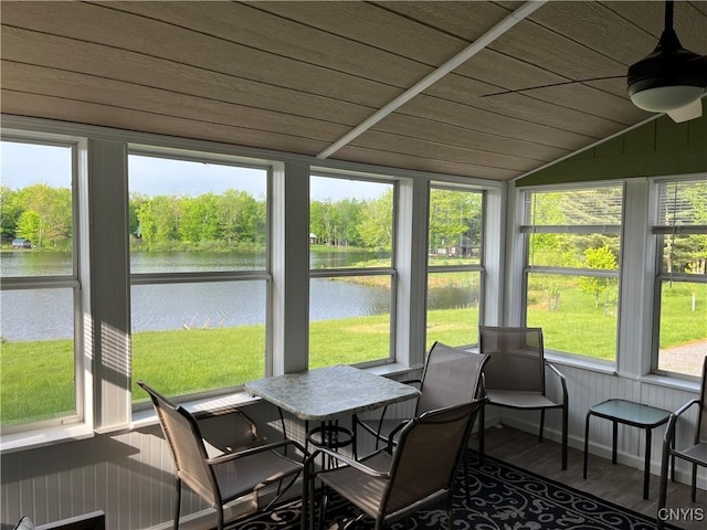 sunroom featuring a water view, vaulted ceiling, healthy amount of natural light, a ceiling fan, and wood finished floors