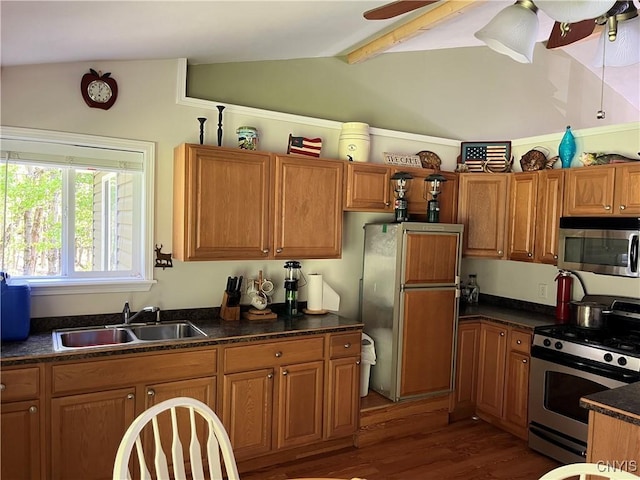 kitchen featuring stainless steel appliances, a sink, brown cabinetry, dark wood-style floors, and dark countertops