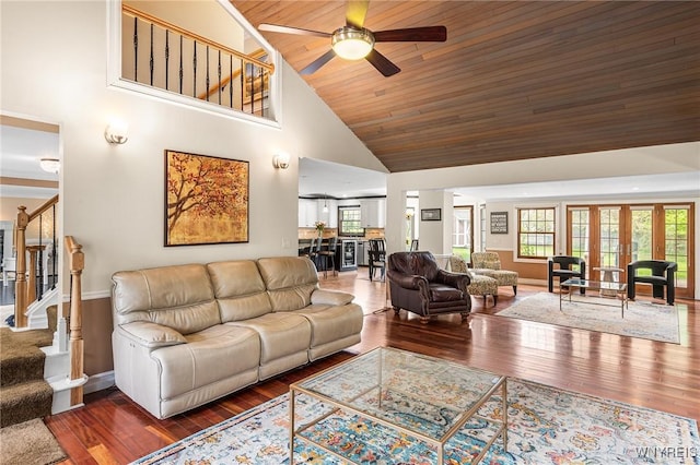 living area featuring high vaulted ceiling, stairway, ceiling fan, wood finished floors, and baseboards