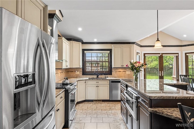 kitchen featuring appliances with stainless steel finishes, cream cabinets, a sink, decorative backsplash, and light stone counters