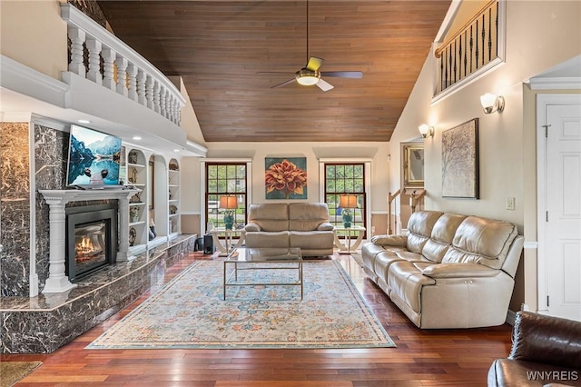 living area featuring a ceiling fan, a high end fireplace, wooden ceiling, hardwood / wood-style floors, and built in shelves