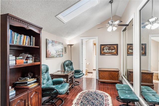 office space featuring vaulted ceiling, ceiling fan, a textured ceiling, dark wood-style flooring, and a skylight