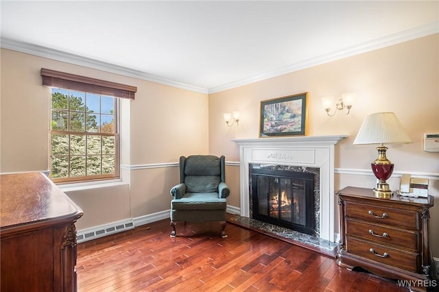 sitting room with wood-type flooring, ornamental molding, a high end fireplace, and baseboards