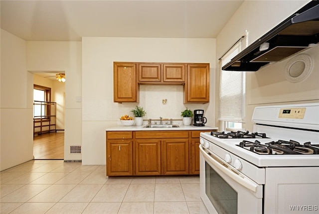 145 Heath St, Buffalo, NY 14214 - kitchen with white gas stove, a sink, light countertops, brown cabinets, and a ceiling fan