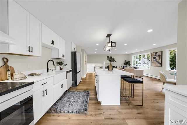 425 W Ln, Lewiston, NY 14092 - kitchen with a sink, freestanding refrigerator, a kitchen bar, white cabinetry, and wood finished floors