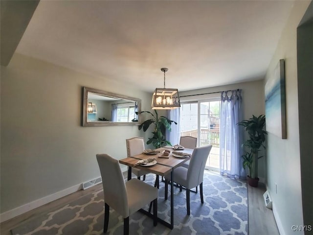 dining area featuring wood finished floors, plenty of natural light, baseboards, and a chandelier