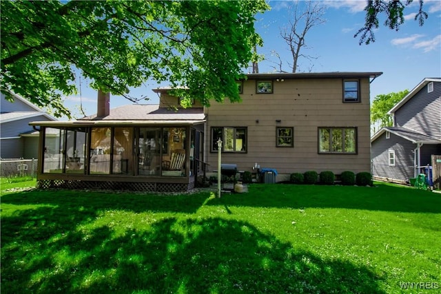 rear view of property with a lawn, a sunroom, and a chimney