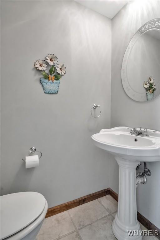 bathroom featuring toilet, baseboards, and tile patterned flooring