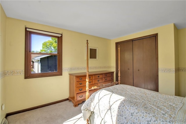 bedroom with a closet, light colored carpet, and baseboards