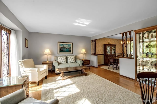 living area featuring wallpapered walls, wood finished floors, and a wainscoted wall