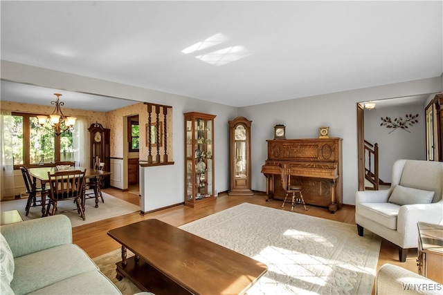 living area with a chandelier, light wood-type flooring, and baseboards