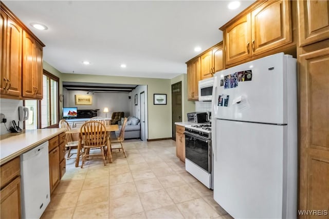 kitchen featuring white appliances, recessed lighting, light countertops, and brown cabinetry
