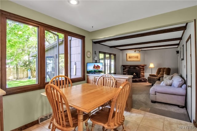 dining space with plenty of natural light, beamed ceiling, light tile patterned floors, a fireplace, and baseboards