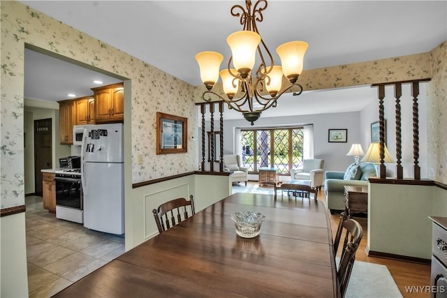 dining room featuring wallpapered walls, a chandelier, and a wainscoted wall