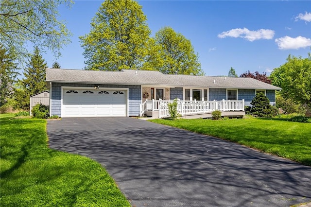 ranch-style house with driveway, an attached garage, a front yard, and a porch