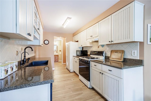 kitchen with gas range oven, a sink, black microwave, light wood-type flooring, and decorative backsplash