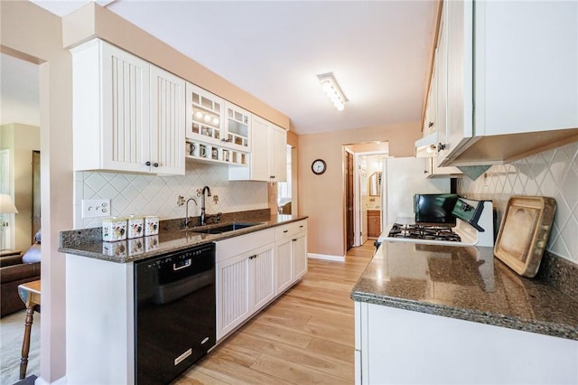kitchen with black dishwasher, a sink, light wood-style floors, white cabinetry, and tasteful backsplash