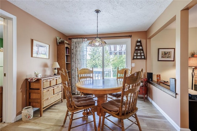 dining room with light wood-style floors, a textured ceiling, and baseboards