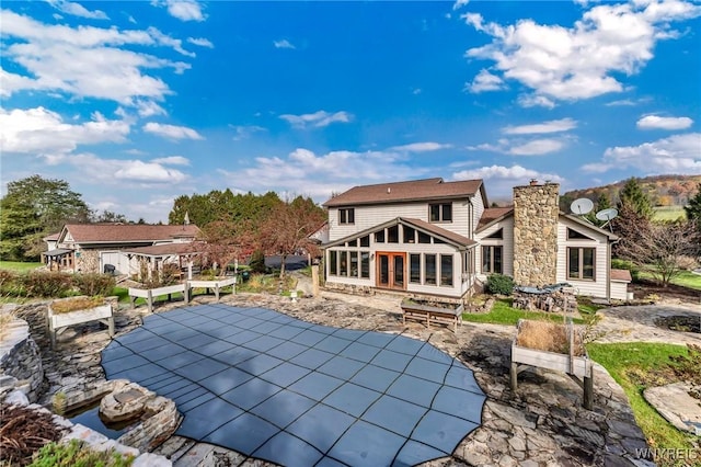 9811 Deer Creek Rd, Genesee, NY 14770 - back of property featuring a sunroom, a patio area, a covered pool, and a chimney