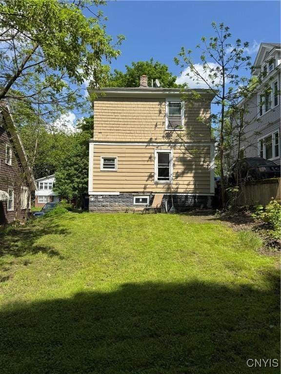 back of property featuring a lawn and a chimney