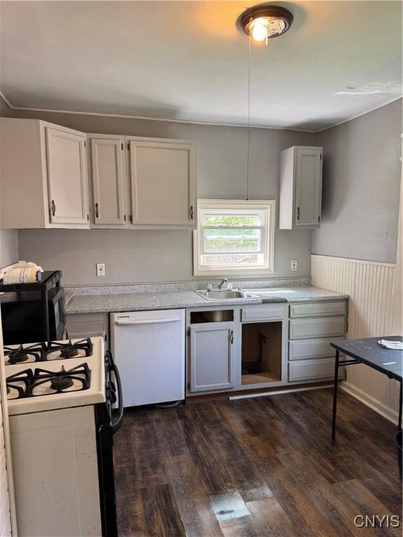 kitchen with white dishwasher, gas stove, light countertops, dark wood finished floors, and wainscoting