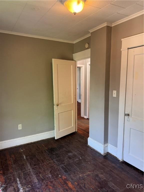 unfurnished bedroom with baseboards, dark wood finished floors, and ornamental molding