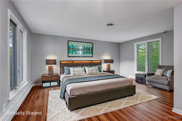 bedroom with a baseboard radiator, wood finished floors, and baseboards